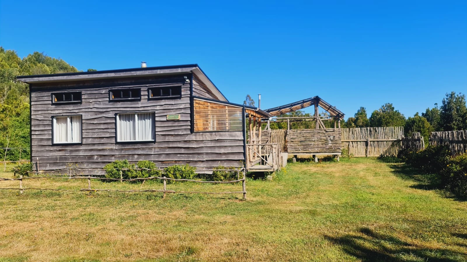 Cabaña de madera oscura con espacio exterior en Paraíso Wilkeco