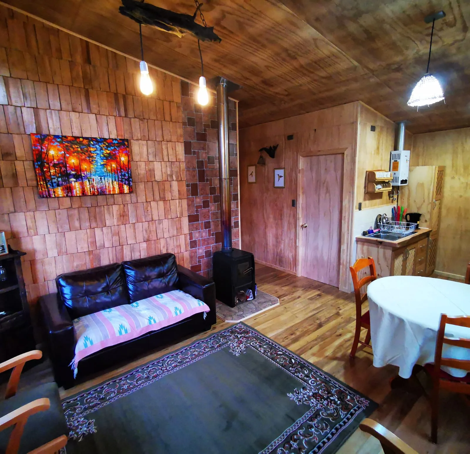 Interior de cabaña equipada con cocina, comedor y calefacción a leña en Paraíso Wilkeco