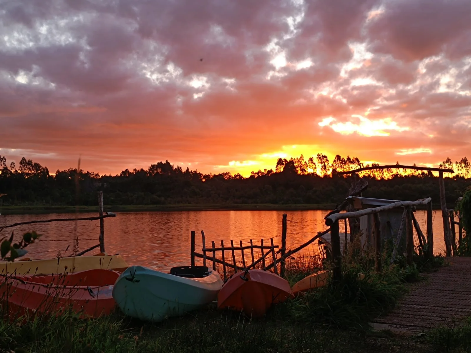 Kayaks junto al agua durante un atardecer intenso en Paraíso Wilkeco