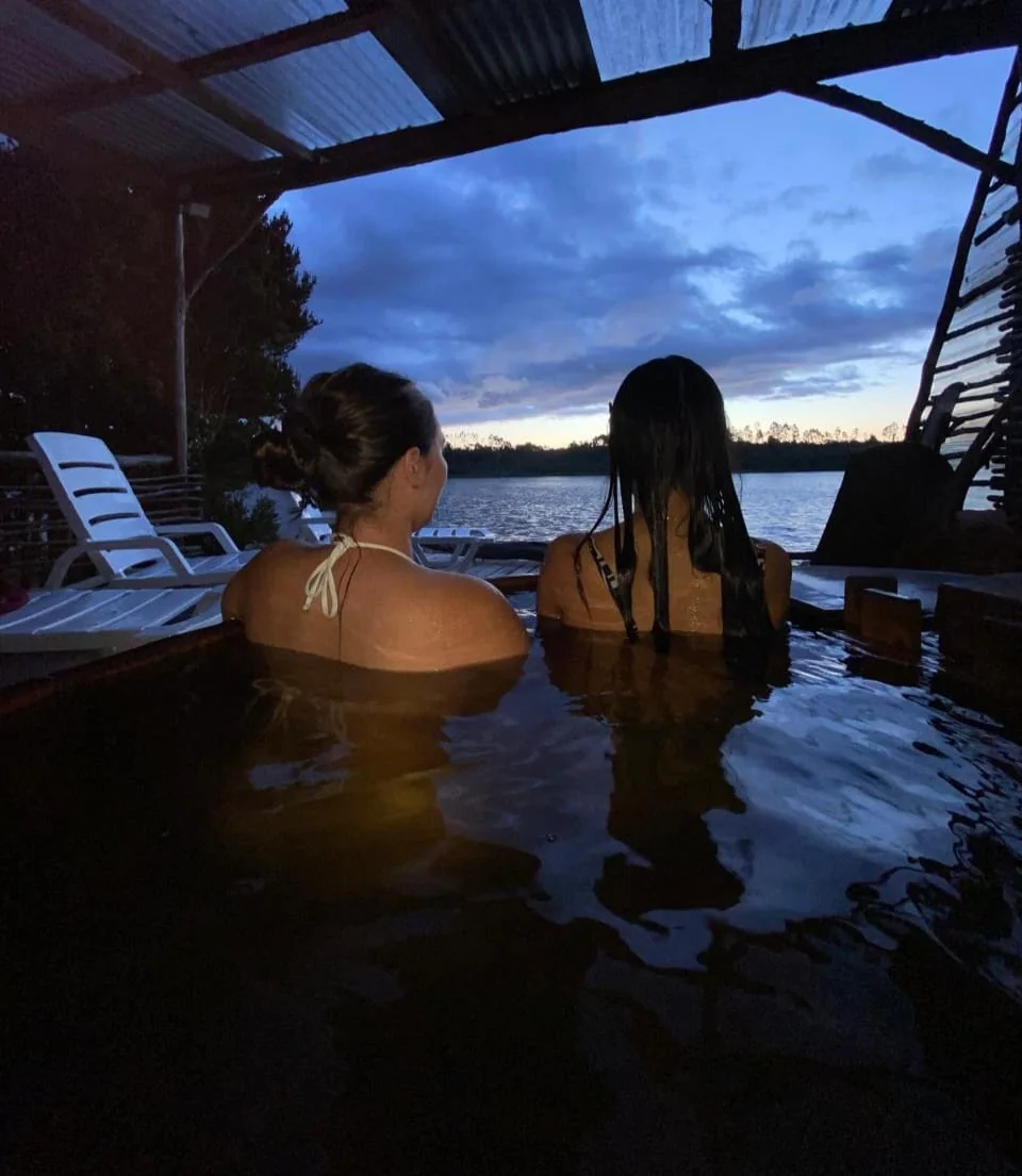 Huéspedes disfrutando una tinaja privada al anochecer con vista al río en Paraíso Wilkeco